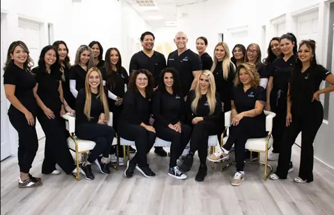 The Evolve team, about twenty people in black Evolve scrubs, smiling together in a bright office hallway